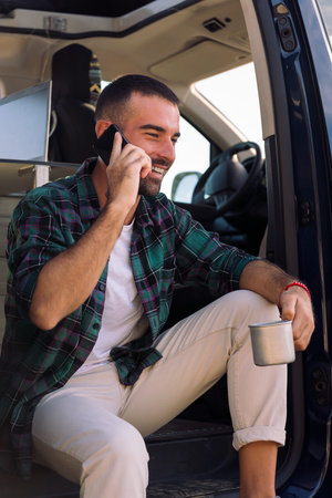 man talking on phone sitting in the door of his vanの写真素材