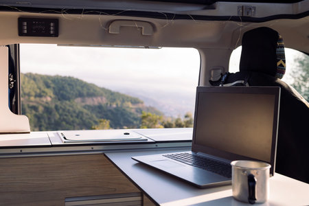 table of a camper van with a laptop and a mugの写真素材