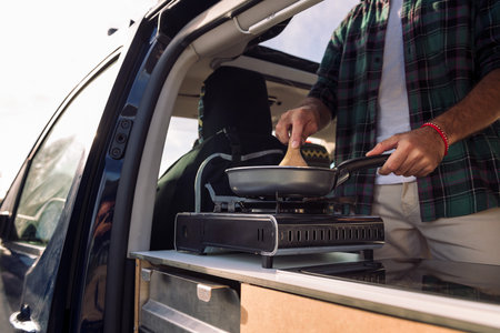 unrecognizable young man cooking in his camper vanの写真素材