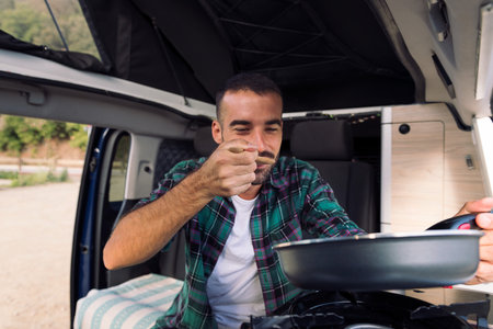 man tasting food he is cooking in his camper vanの写真素材