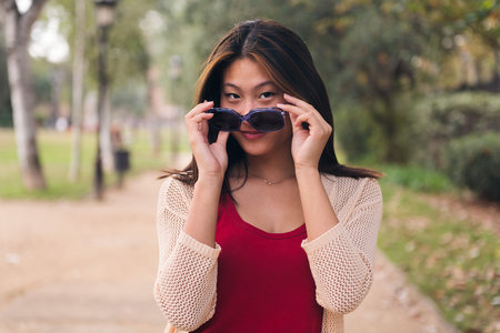 woman looking at camera with mischief over glassesの写真素材