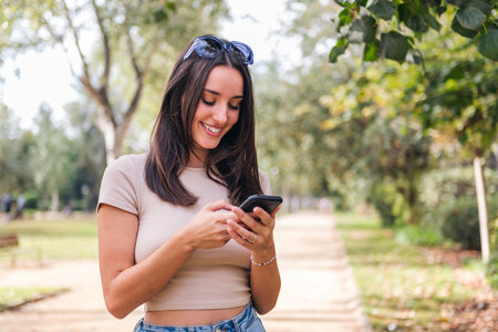 smiling woman typing on mobile phone in a parkの写真素材