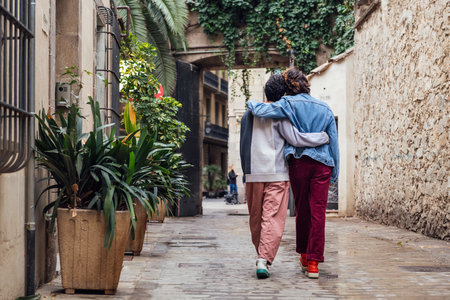 male couple walking embraced along a streetの写真素材