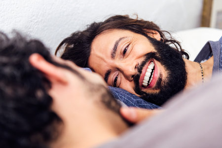 smiling happy man relaxed in bed with boyfriendの写真素材
