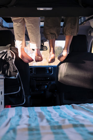 feet dangling off the elevated bed of a camper vanの写真素材