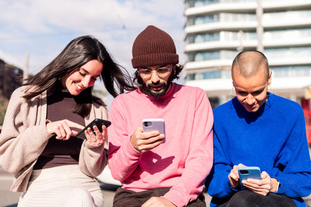 three young adults using mobile phones at cityの写真素材
