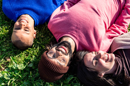 three friends enjoying the sun lying in the grass