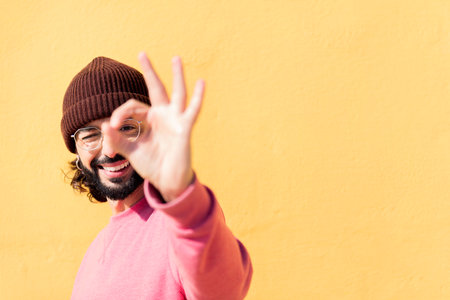man doing ok sign with hand in a yellow backgroundの写真素材