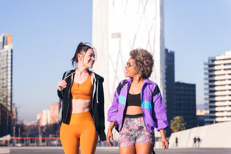 two women in sportswear talking while walkingの写真素材