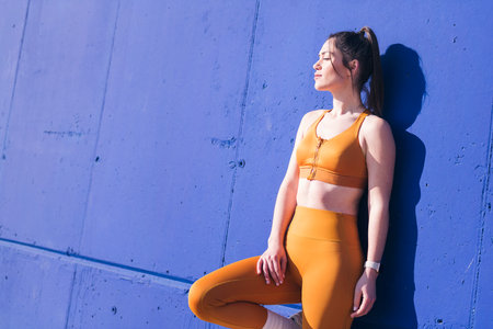 sportswoman sunbathing leaning in a blue wallの写真素材