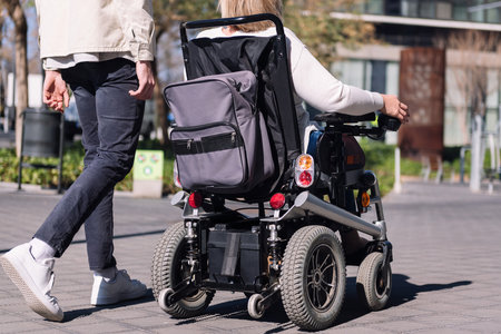woman using wheelchair with a man taking a walkの写真素材
