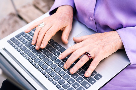 hands of a senior woman typing on a laptopの写真素材