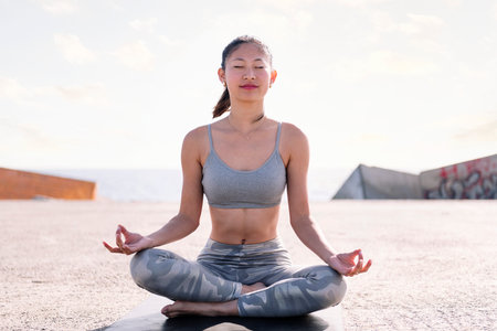 woman doing yoga meditation sitting by the sea