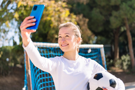 woman taking selfie while holding a soccer ball