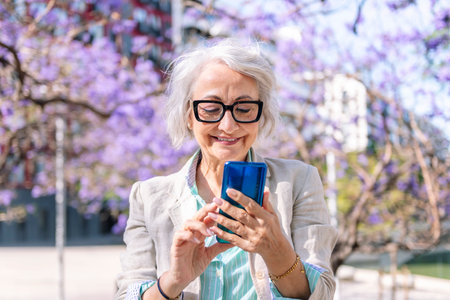 mature woman smiling happy typing on mobile phoneの写真素材