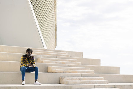 black man sitting on a staircase with his phone