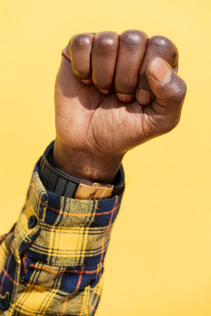 raised fist of a black man on a yellow backgroundの写真素材