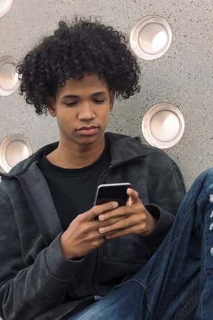 teenager with curly hair using mobile phoneの写真素材