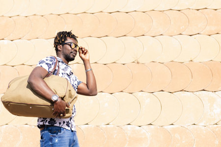 black man with a travel bag fits his sunglasses