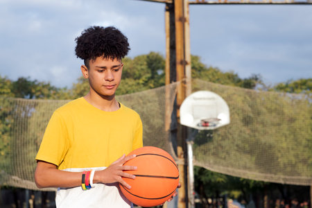 latin teen player with basketball on sports groundの写真素材