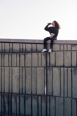 thirsty woman drinking on roof after workoutの写真素材