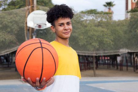 latin teen player with basket ball on sport groundの写真素材