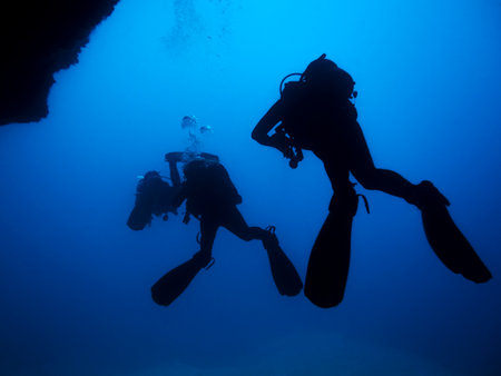unrecognizable divers exploring blue oceanの写真素材
