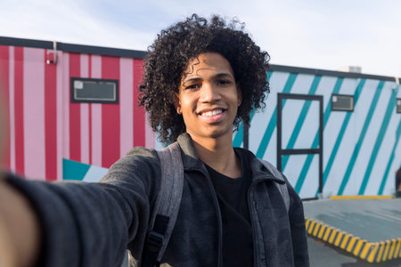 selfie photo of a smiling curly haired teenager