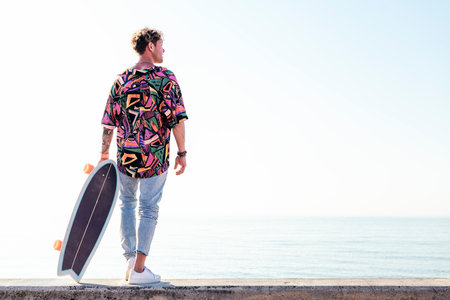 male skater in trendy outfit carrying skateboardの写真素材