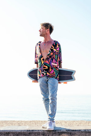 skater in trendy summer outfit carrying skateboard