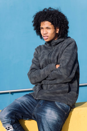 teenager with curly hair sitting with arms crossedの写真素材