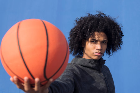 unemotional teen offering basketball ball