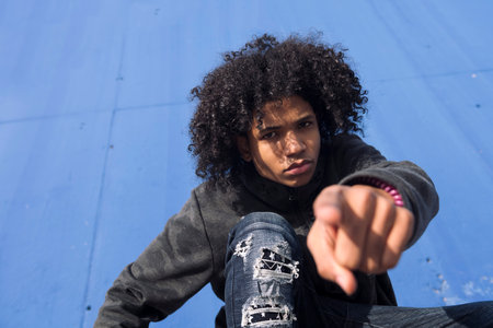 teen male with curly hair pointing at camera
