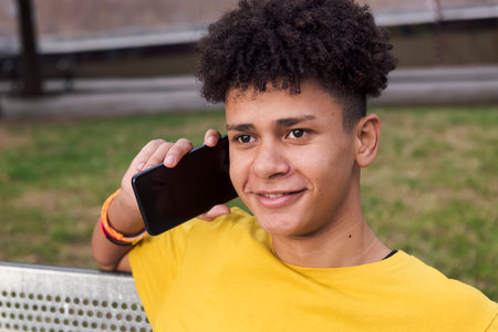 smiling latin teen male talking on mobile phoneの写真素材