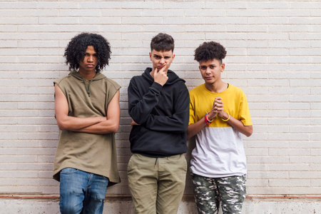 teenager friends leaning against white brick wallの写真素材