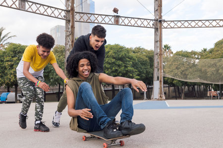 multiethnic teenagers riding friend on skateboardの写真素材