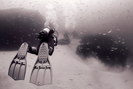 scuba diver in wetsuit diving near bottom of seaの写真素材