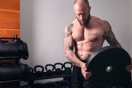 strong bodybuilder with heavy weight plate in gymの写真素材