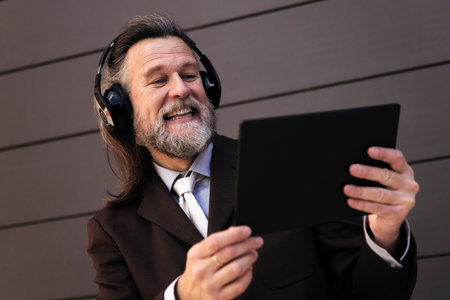 mature man laughing using tablet and headphonesの写真素材