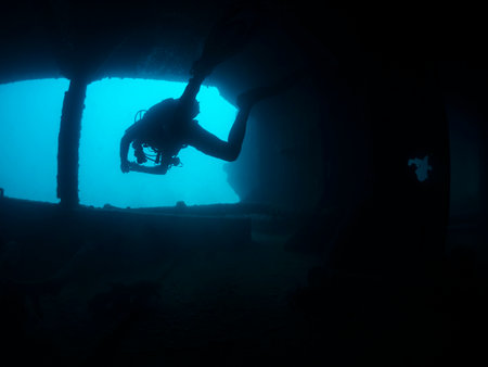 scuba diver diving in the dark waters of shipwreck