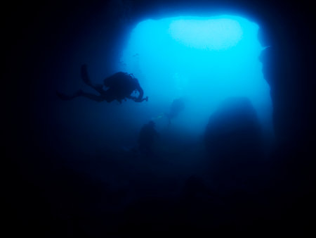 group of scuba divers diving in a dark caveの写真素材