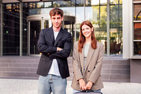 man and woman smiling in front of office building