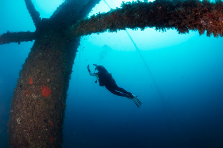diver diving next to a sunken structure in the seaの写真素材