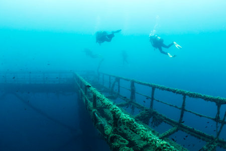 divers diving over wreck of a structure submergedの写真素材