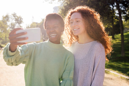 two happy young women taking a selfie with phoneの写真素材