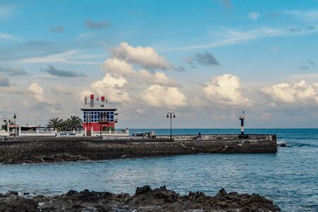 fishing port of lanzarote attached to a rocky cove on the horizon you can see big clouds and a calm seaの写真素材