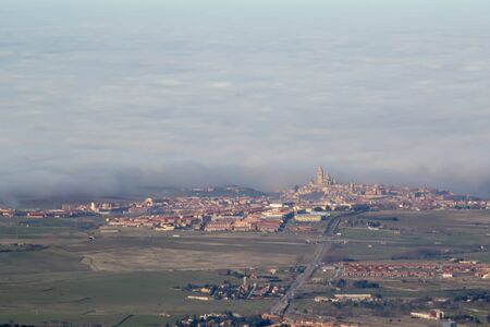 horizontal landscape of the city of segovia, a foggy day and you can see how the city is disappearing, you can recognize its cathedral and the part of the province that overlooks the mountain, the rest is a thick blanket of fogの写真素材