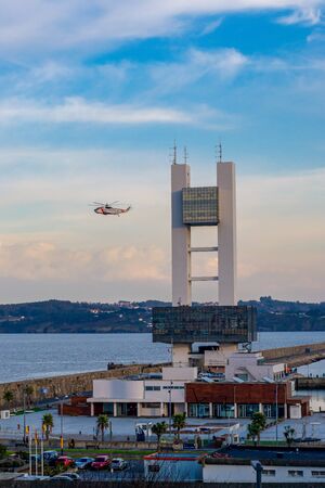 vertical landscape of the maritime control tower of coruÃ±a, it is also the entrance to the port, you can also see the dock, and the surroundings of the H and a nice skyの写真素材