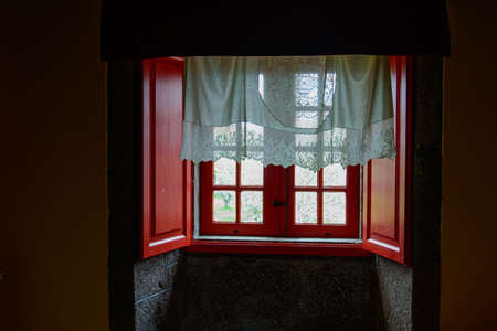 Old red window, from a dark room that lets in the dawn lightの写真素材