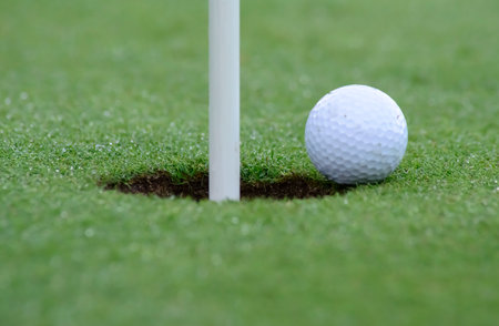 It is a horizontal photograph in which the golf ball is perfectly focused on the edge of the holeの写真素材